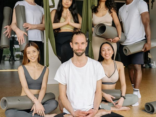 Diverse group of people smiling and preparing for a yoga class.